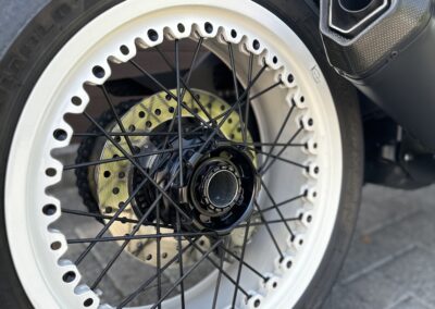 Nahaufnahme, die das Rad und den Reifen eines Motorrads zeigt. Beschaffenheit, den Zustand und die Bauweise von Rad und Reifen eines Motorrads gibt.