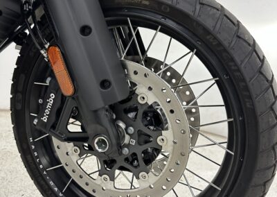 Eine detaillierte Nahaufnahme, die das Vorderrad eines schwarzen Motorrads hervorhebt.