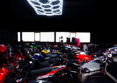 Ein Panoramablick auf einen überdachten Motorradparkplatz, beleuchtet durch Neonbeleuchtung.